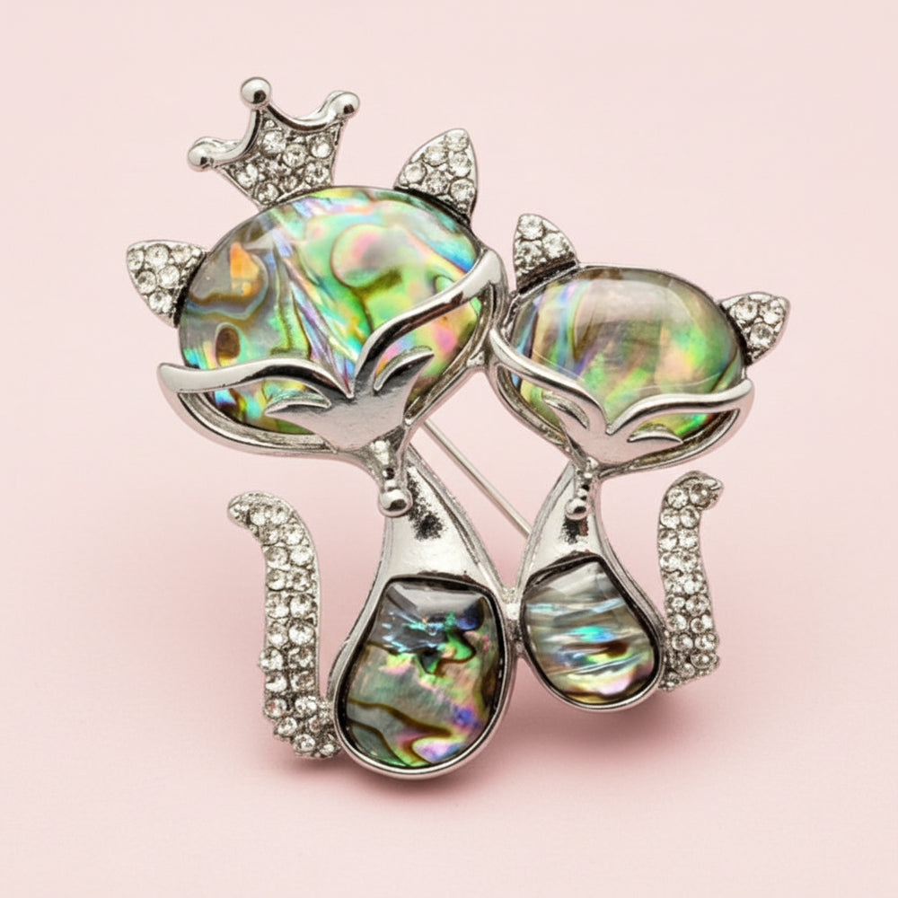 Double cat brooch with iridescent stones and rhinestones on a light background 