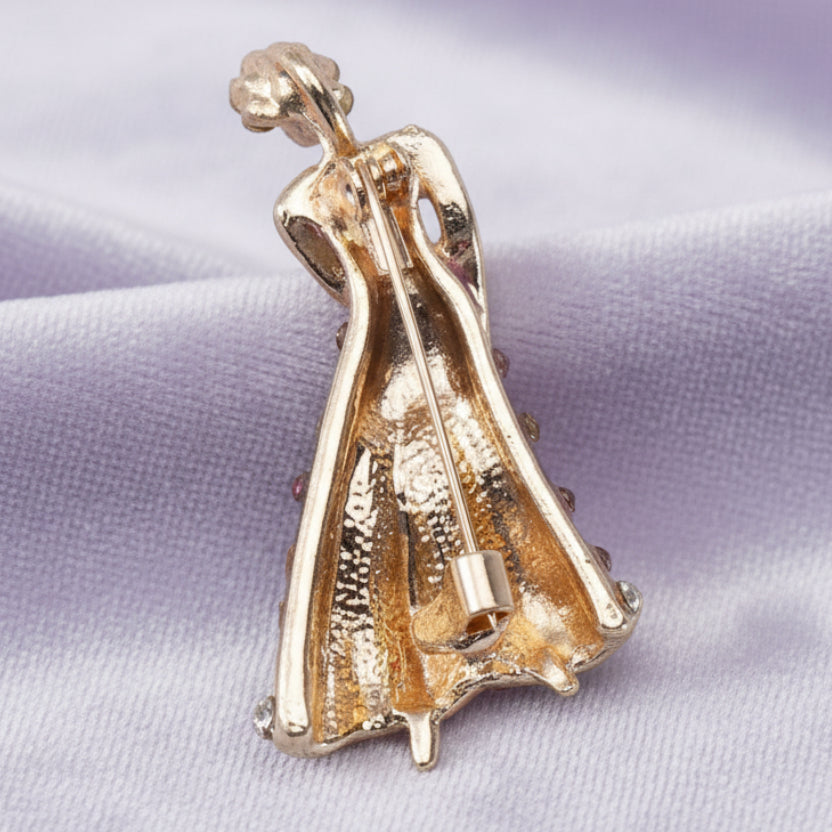 Backside of blue dancing lady brooch  on a light lilac velvet background