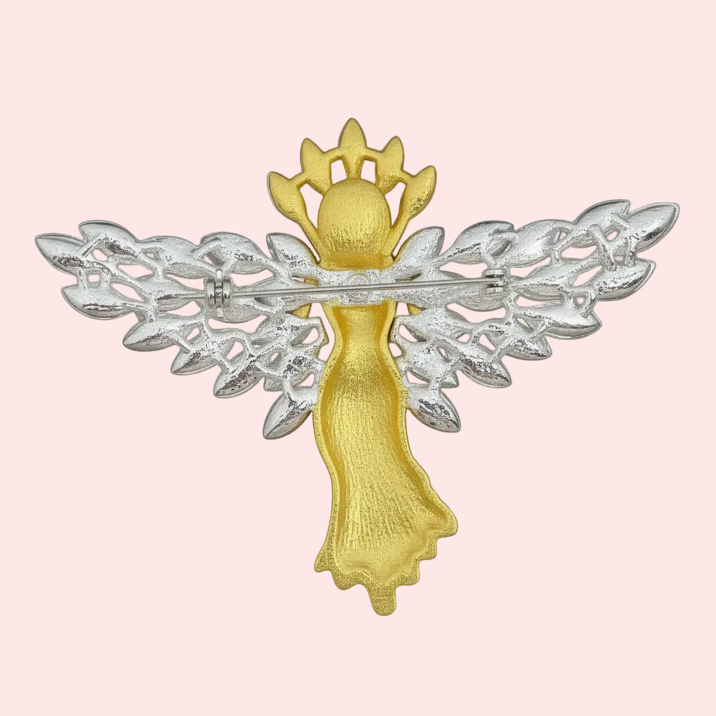 Backside of gold with crystal angel brooch on a pastel background