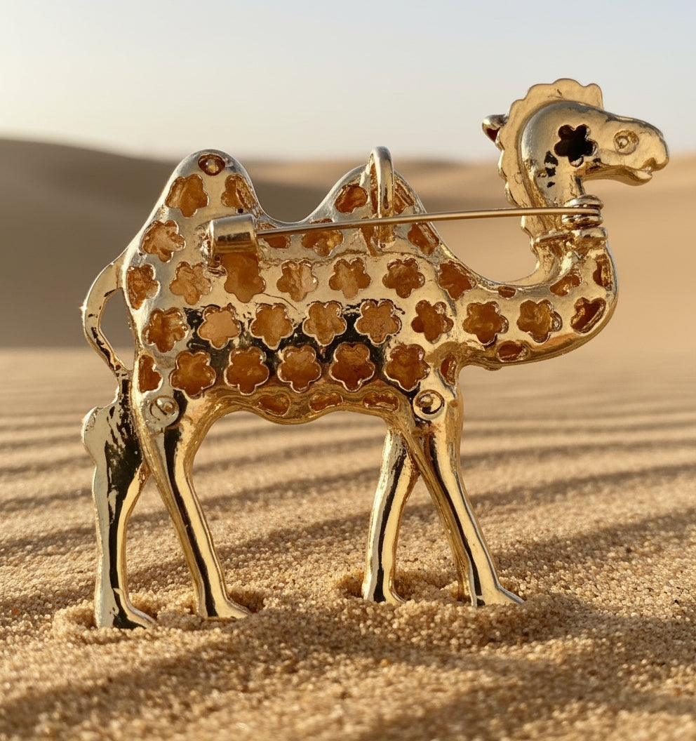 Backside of gold camel brooch on a sandy background