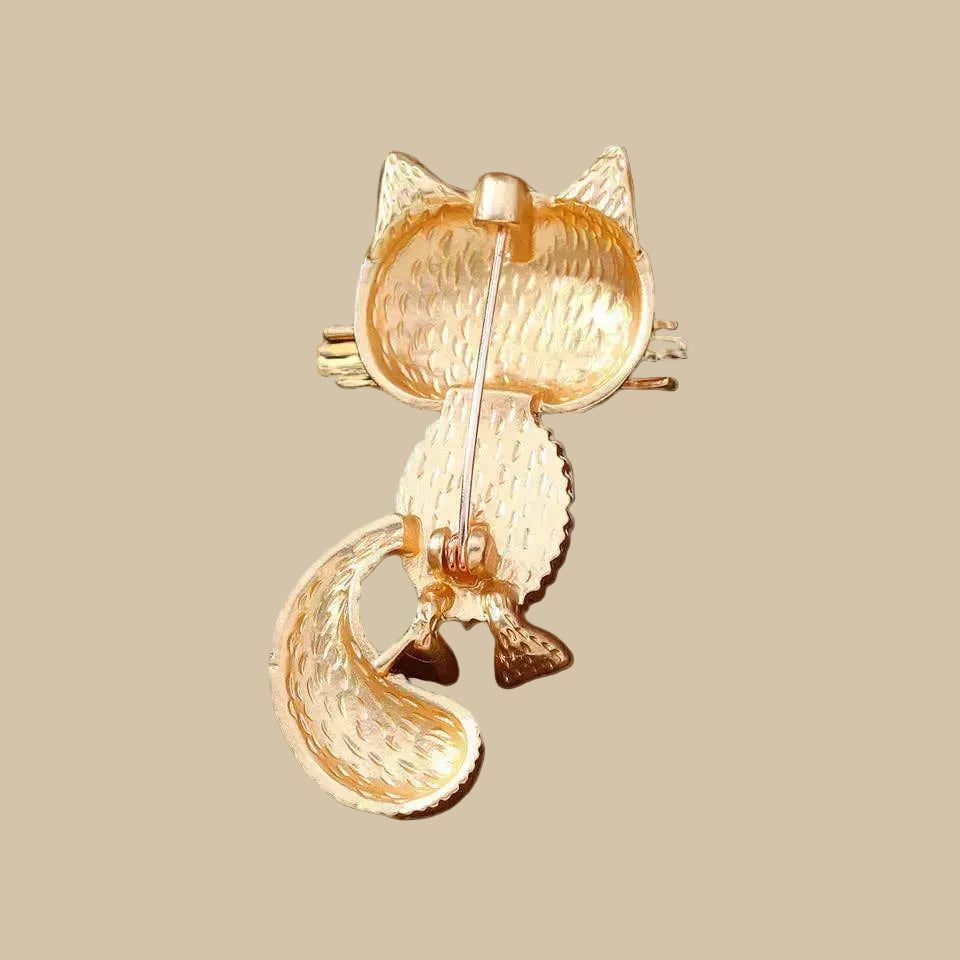 Backside of retro golden cat brooch on a beige background
