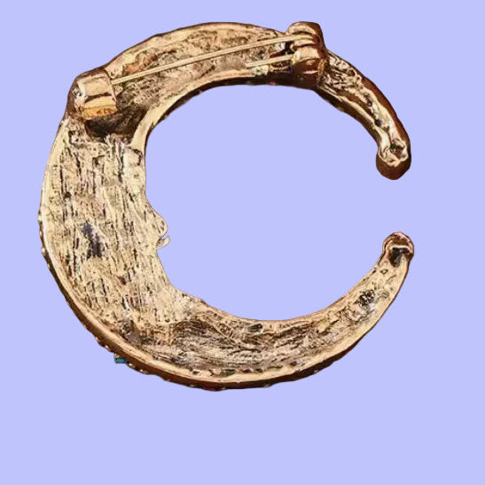 Back of fantasy moon brooch with colorful gemstones on a gradient background