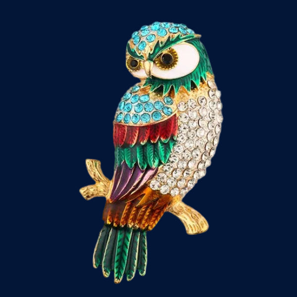 Colorful owl-shaped brooch perched on a golden branch on a dark blue  background