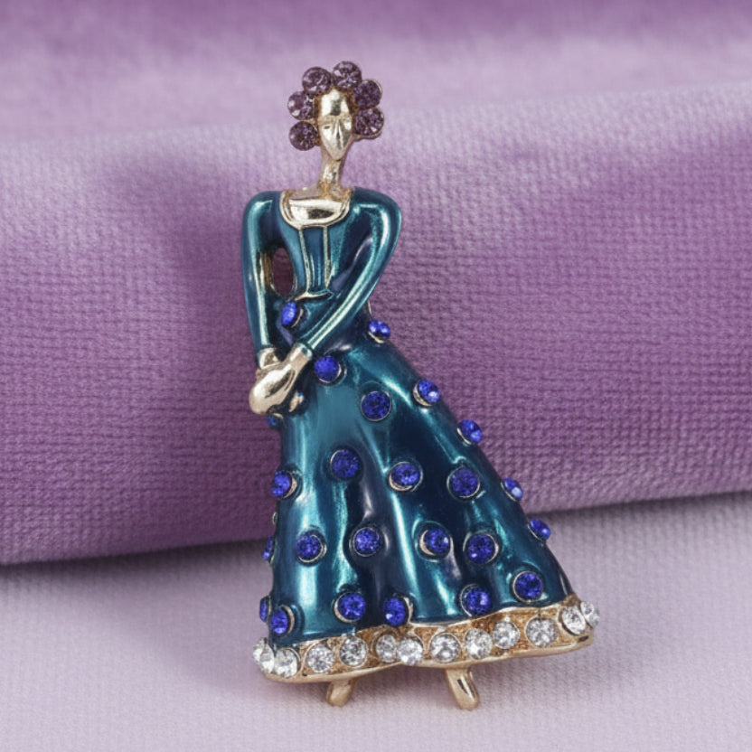 Blue dancing lady brooch with purple accents on a light lilac velvet background