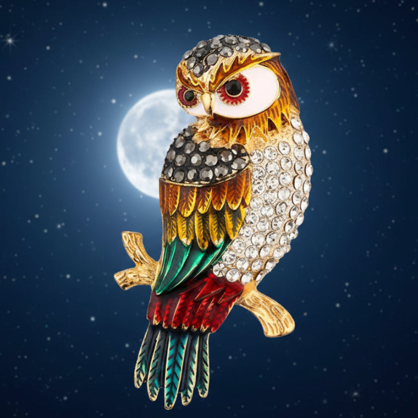 Colorful rhinestone owl brooch on a golden branch on a night sky background