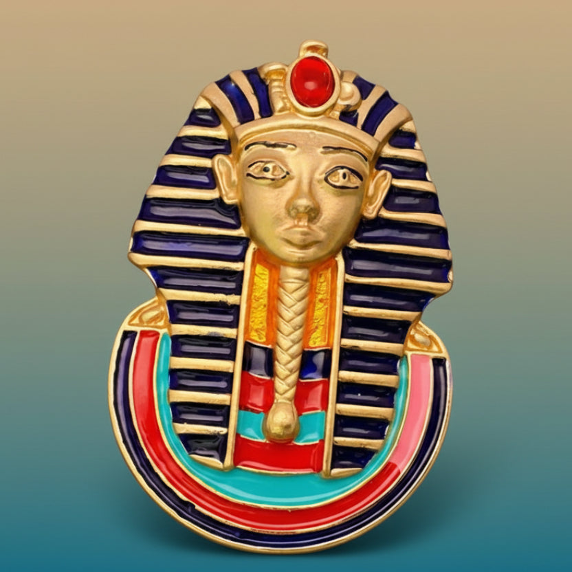 Decorative brooch with Egyptian sphinx design on a light blue background