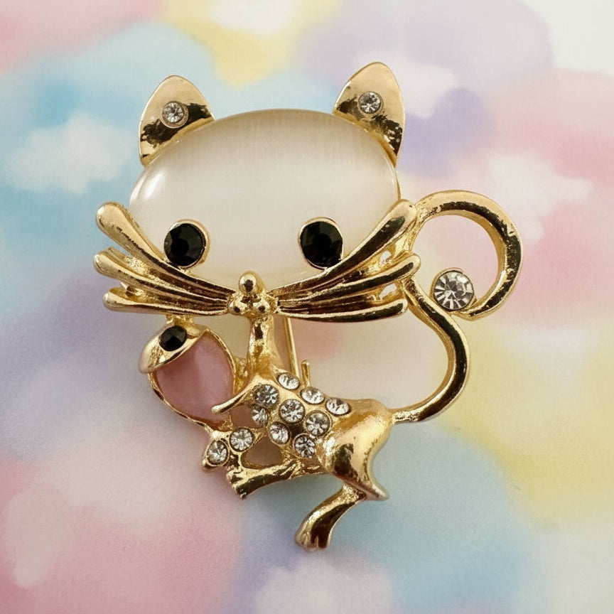 Moonstone mouse brooch with gold accents and rhinestones on a colorful background