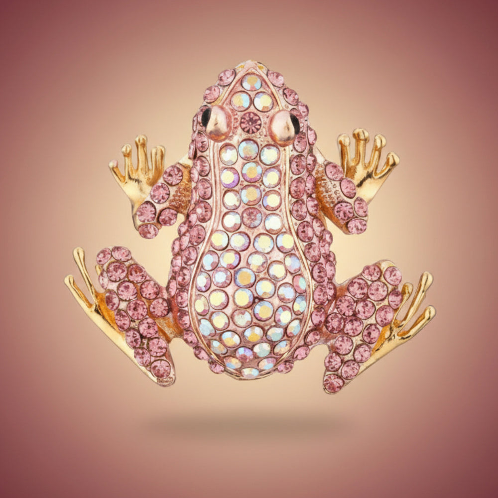 Decorative pink rhinestone frog brooch on a pastel pink background