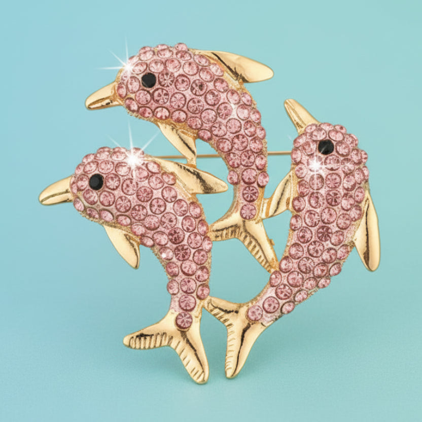Triple dolphin brooch with pink rhinestones on a light blue background