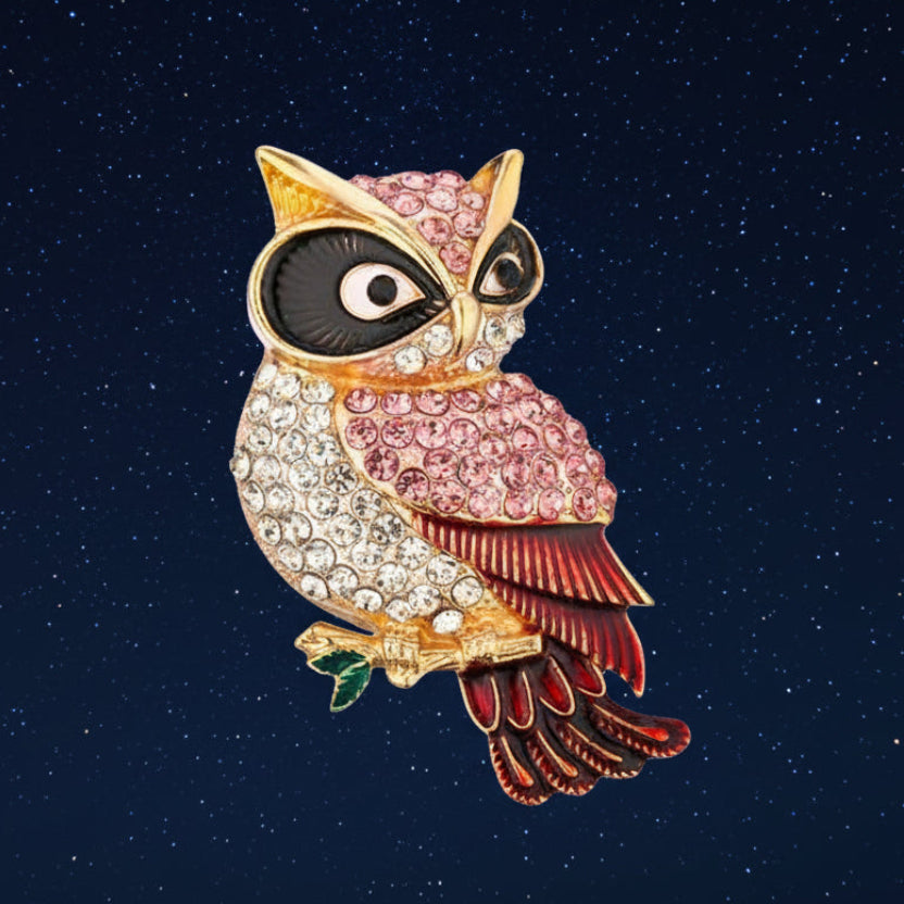 Colorful red accented owl brooch perched on a golden branch on a night sky background