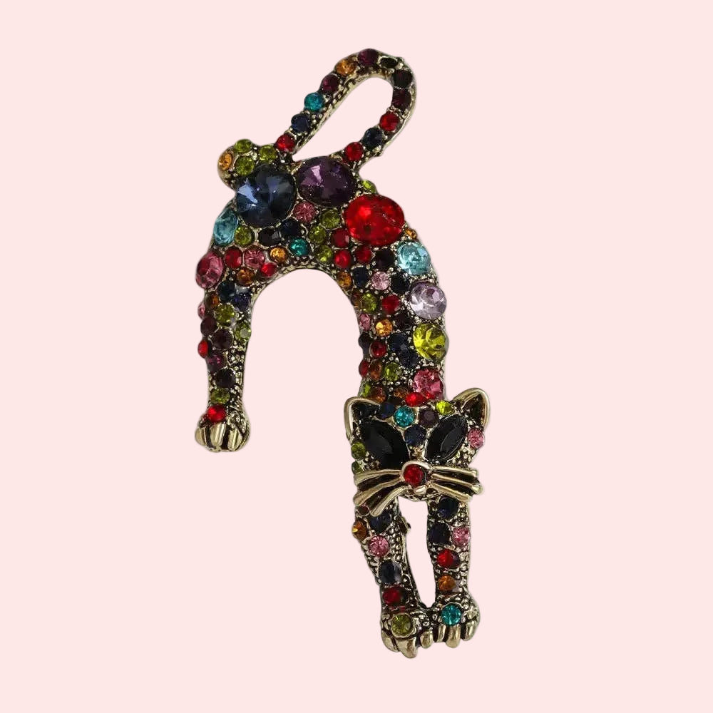 Colorful cat-shaped brooch with gemstones on a white background