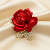 Red rose brooch with gold leaves on a ivory satin background