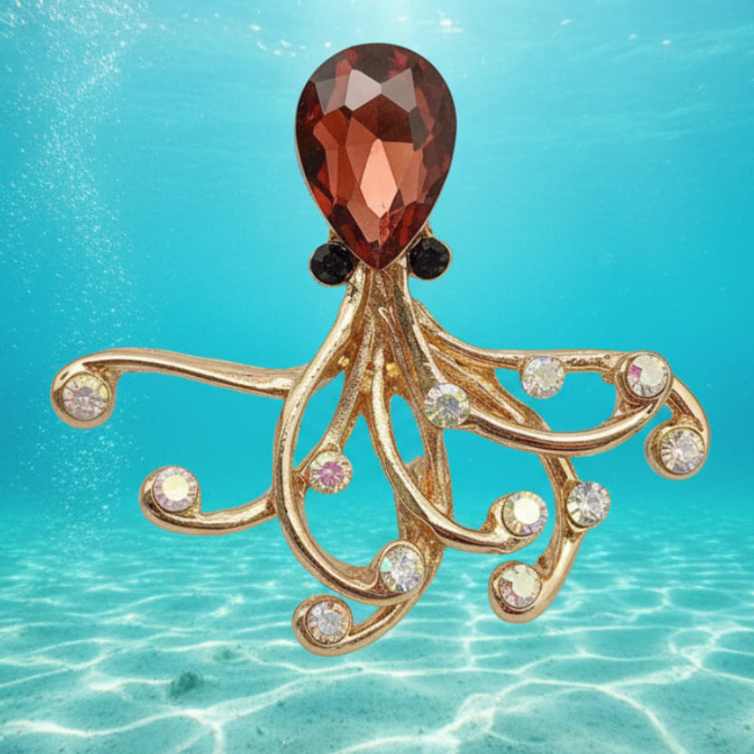 Golden octopus brooch with a red glass head on a underwater background