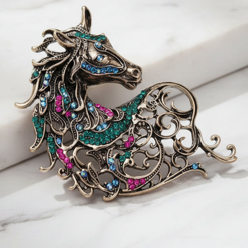 Decorative horse-shaped brooch with gemstones on a light background