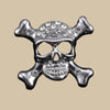 Silver skull and crossbones brooch pin with clear crystal stones on a beige background