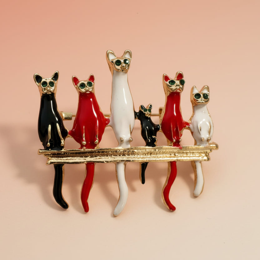 Colorful six-cat brooch on a light pastel pink background