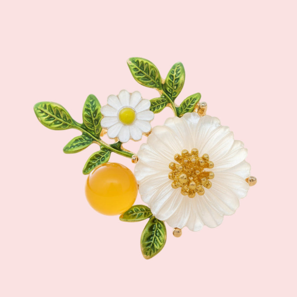 Floral brooch with white flowers, green leaves, and a yellow berry on a pink background