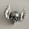 Silver skull brooch with wings on a light gray background