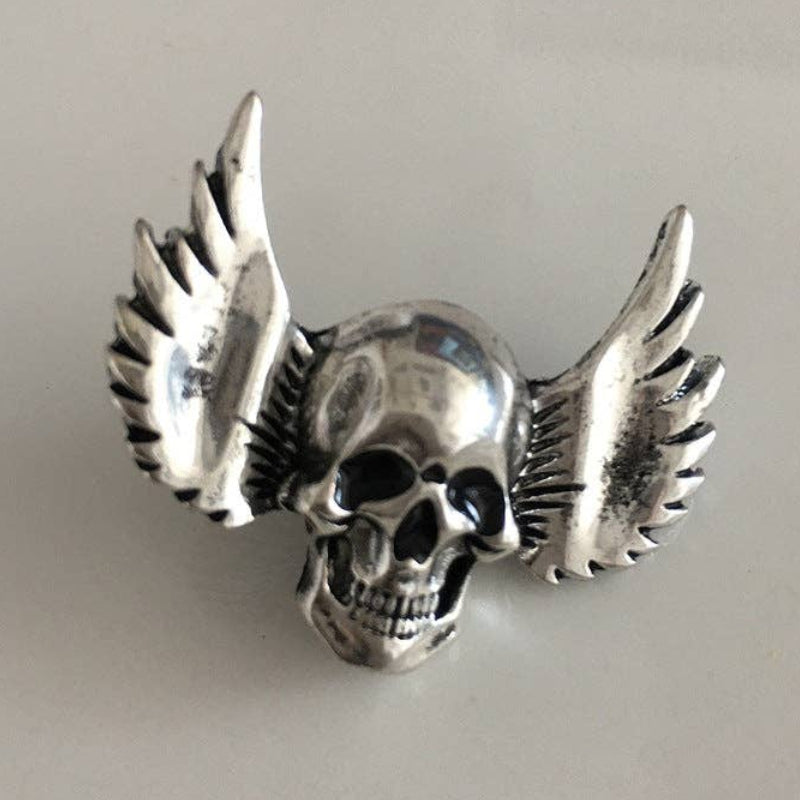Silver skull brooch with wings on a light gray background